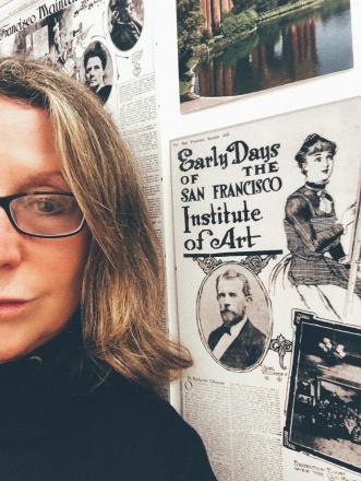 Balliger in front of old poster with text: Early Days of the San Francisco Institute of Art