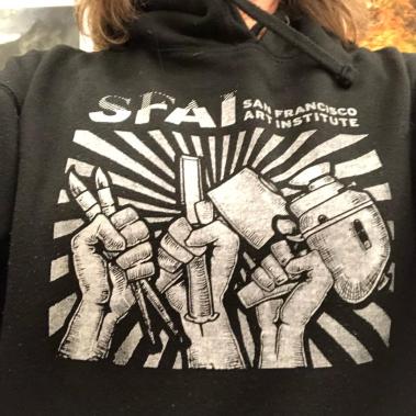 SFAI sweat shirt with three fists clenching paint brushes, sculpture tools, and camera